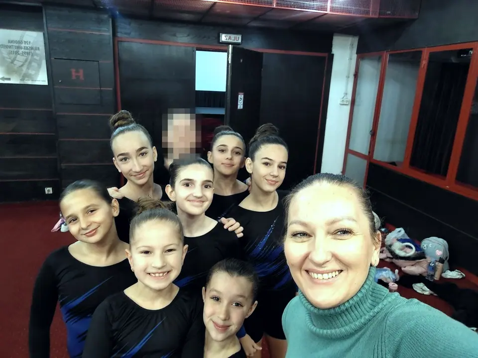 Takmičarke aerobne gimnastike u crnim trikoima i trenerica prave zajednički selfi